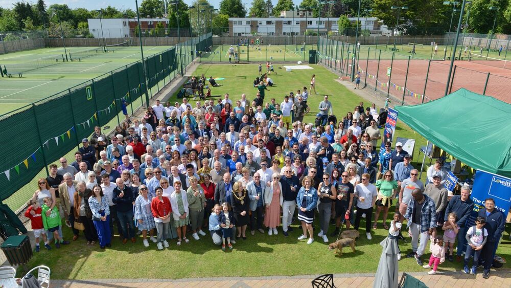 A large group photo of members on the tennis courts